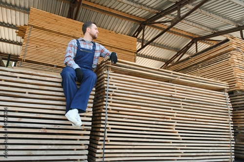 Carpenter in uniform check boards on sawmill