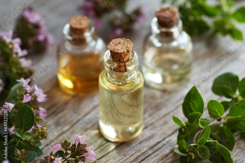 Bottles of essential oil on a table with blooming oregano twigs