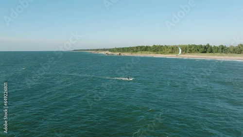 Establishing aerial view of a group of people engaged in kitesurfing, sunny summer day, high waves, extreme sport, Baltic Sea Karosta beach (Liepaja), birdseye drone dolly shot moving right
