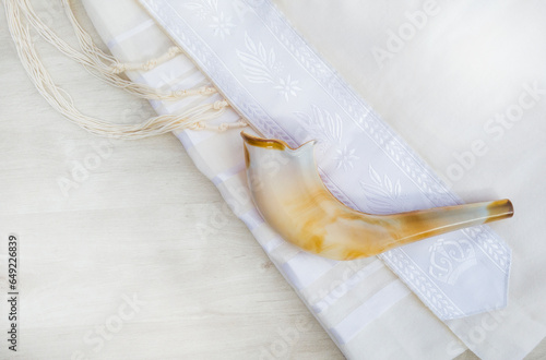 A shofar is placed on a tallit on a white surface. photographed from above.   A symbol of the Rosh Hashanah holiday. Suitable for shana tova greeting card and Yom Kippur.
with free space for text
