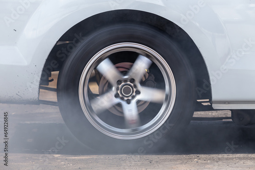 Close up car wheel with smoke on the asphalt road speed track, Car wheel drifting and smoking on track, Car wheel spinning. © Darunrat