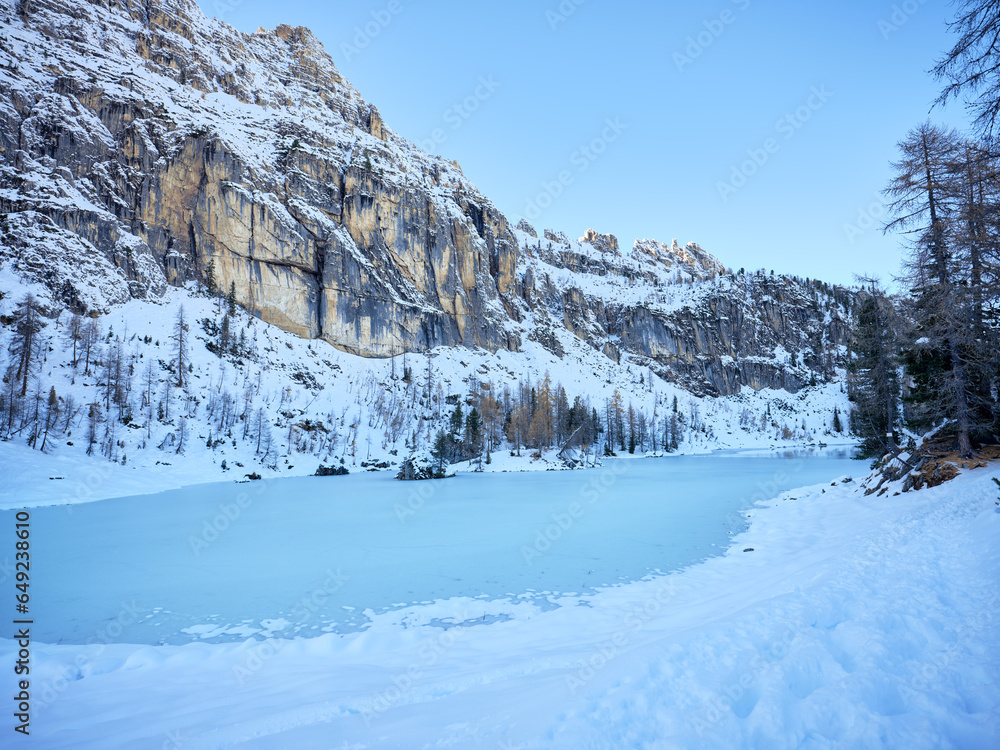 Autumn landscape in the woods of the Dolomites, overlooking the frozen Federa lake and the snow-capped Croda da Lago mountain range in Cortina d'Ampezzo, Veneto, Italy, Europe. 