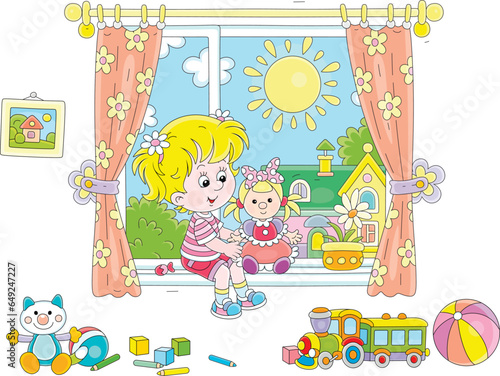 Happy little girl with her funny doll and other toys in a nursery room by a window with curtains and a sunny summer landscape in a background