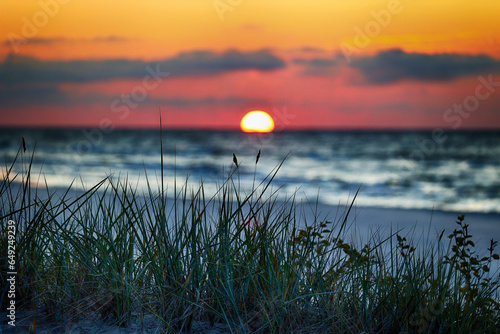 Zachód słońca nad morzem na tle traw.