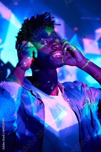 Smiling black man listening to music in headphones in club