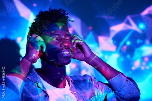 Smiling black man listening to music in headphones in studio © ADDICTIVE STOCK CORE