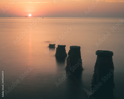 Fototapeta Naklejka Na Ścianę i Meble -  Long exposure of groynes in the sea at sunset