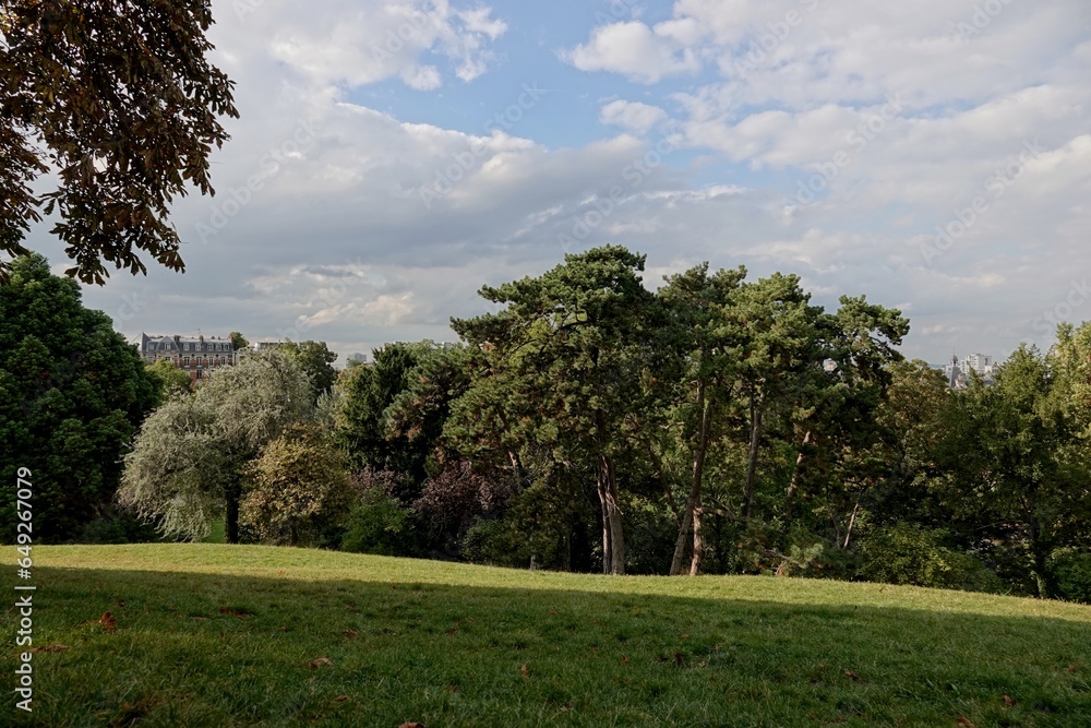 Vue du parc des Buttes-Chaumont avec ciel bleu et gros nuages blancs Vue du parc des Buttes-Chaumont avec ciel bleu et gros nuages blancs