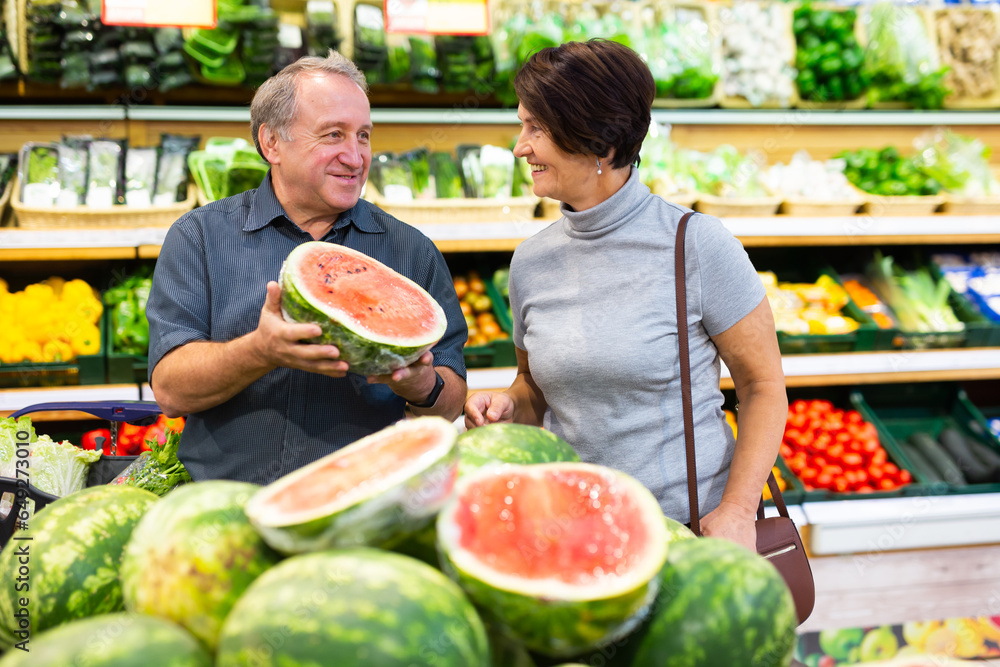 Mature woman and man selecting watermelon in greengrocer