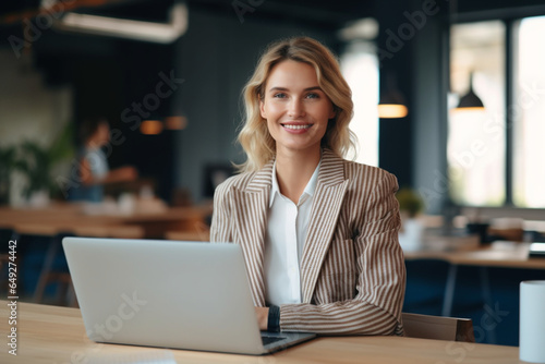 A Happy Beautiful Blonde Businesswoman Looking At Camera While Working On Her Computer