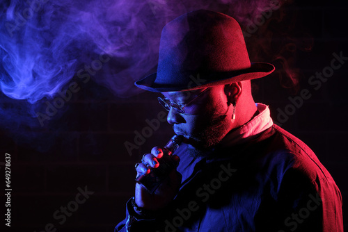 Bearded man smoking vape in dark room