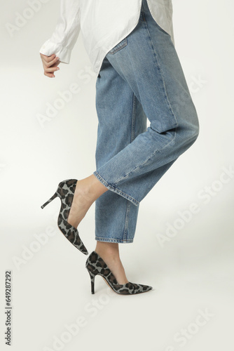 Studio shot of female model wearing wide leg jeans and leopard high heels. Classic timeless fashion items.	 photo