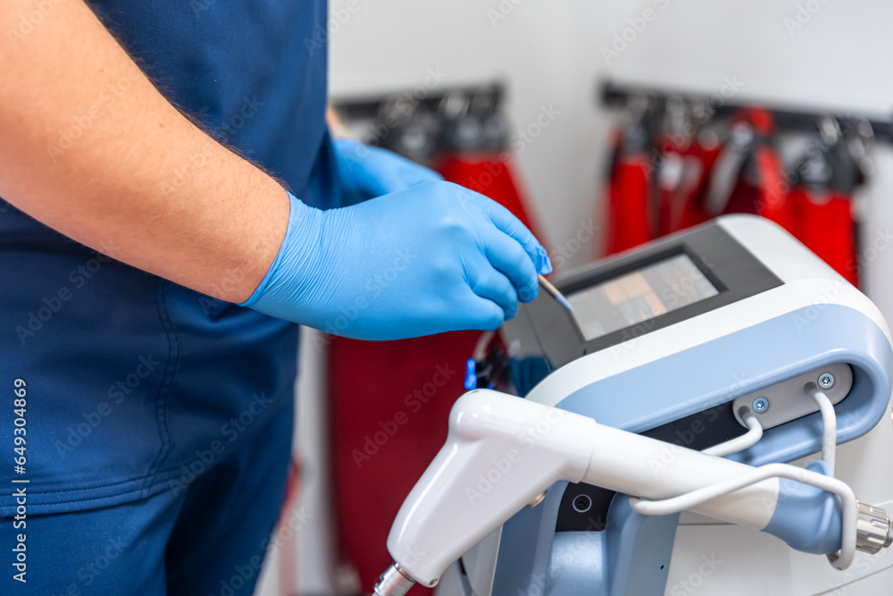 Shock wave therapy device with male doctor hands in rubber gloves. Shock wave therapy device with male doctor hands in rubber gloves.