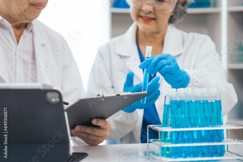 Senior scientists analyzing pharmaceuticals  asian people  senior man and woman  experienced experts in science  conducting pharmaceutical research in modern lab setting with powerful microscope.