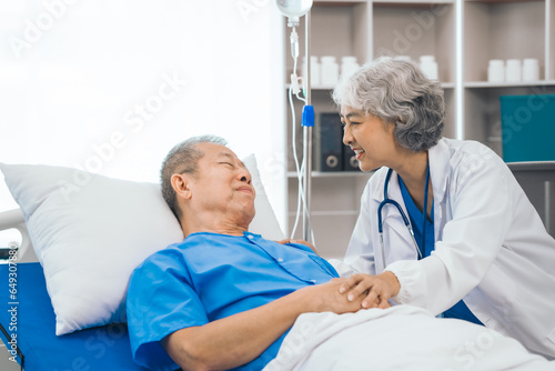 Fototapeta Naklejka Na Ścianę i Meble -  Senior elderly male patient and asian people mature woman doctor, showcasing importance of healthcare expertise and patient support. caring senior doctor assisting elderly patient in hospital bed