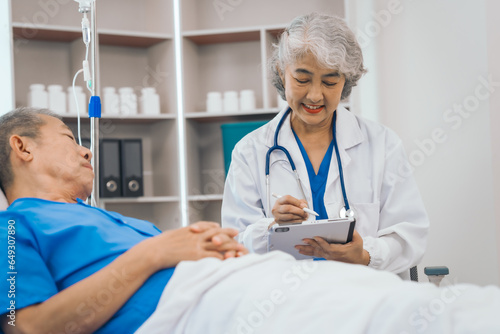 Senior elderly male patient and asian people mature woman doctor, showcasing importance of healthcare expertise and patient support. caring senior doctor assisting elderly patient in hospital bed