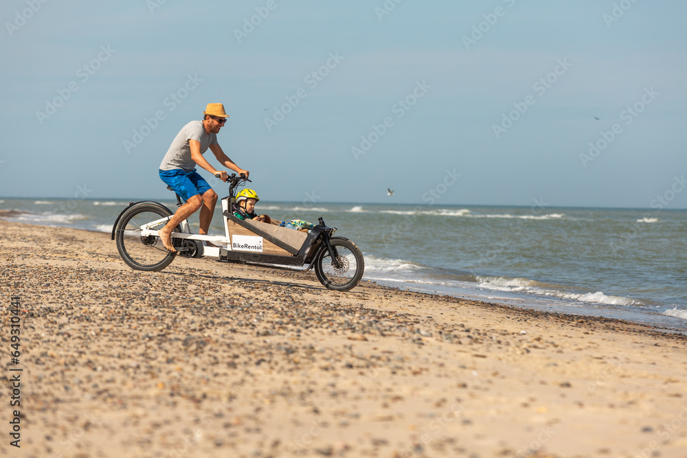 Fototapeta premium Papa und Kind haben Spaß mit dem Lastenrad am Strand,Skagen,Dänemark
