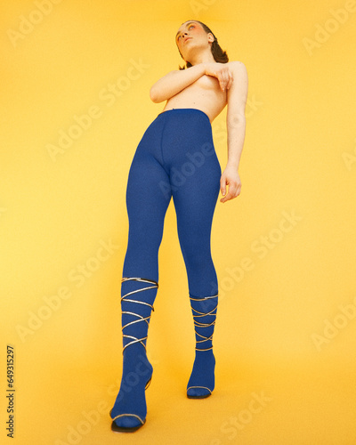 Vibrant fashion shoot featuring a girl in striking blue stockings against a bold yellow backdrop, exuding chic and playful elegance. (ID: 649315297)