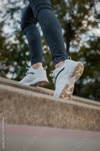 White sneakers on the feet of a girl in black jeans on the street