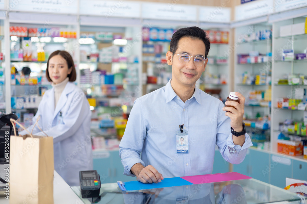 Pharmacy Drugstore. Portrait Professional Pharmacist handsome asian man showing the medicine bottle at pharma store. Health and wellness center