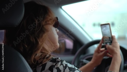 Woman in car taking photo on smartphone for posting in social media. Female with mobile phone inside auto interior