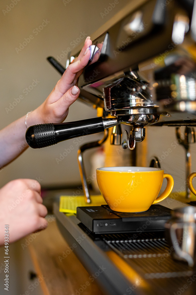 woman hand making cappuccino on coffee machine to cup in bar