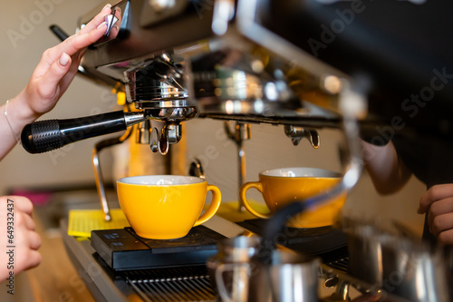 woman hand making cappuccino on coffee machine to cup in bar
