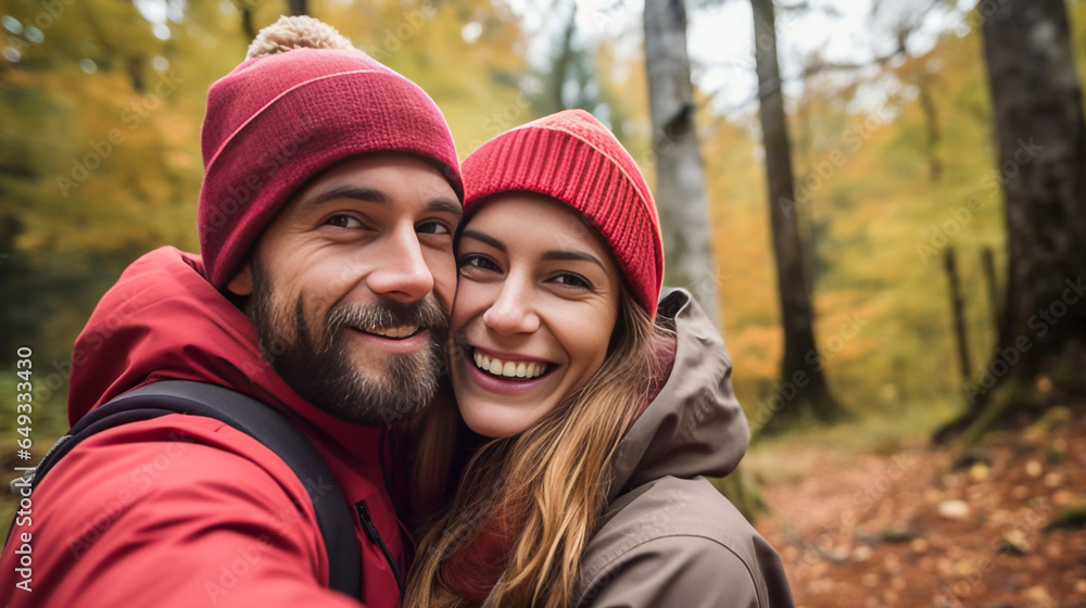 Fototapeta premium stockphotography, copy space, Attractive couple taking a selfie in a forest in autumn. Outdoors activity. Young couple walking outdoors, exploring nature. Autumn walk.
