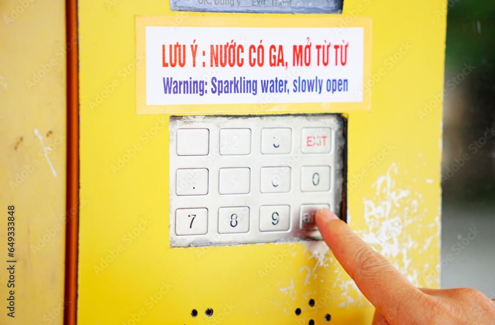 Cropped finger pressing on vending machine number pad to order drinks