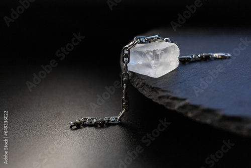 A silver chain lies on a large transparent stone