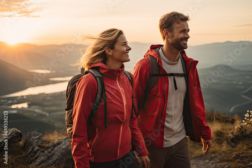 Hiking couple looking enjoying sunset view on hike during trek in mountain nature landscape at sunset. Active healthy couple doing outdoor activities.