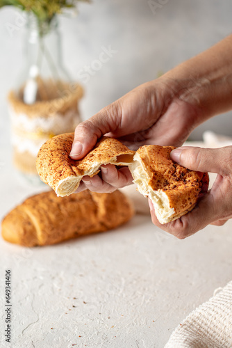 manos partiendo un pan de queso por la mitad sobre una mesa blanca con tematica de desayuno 