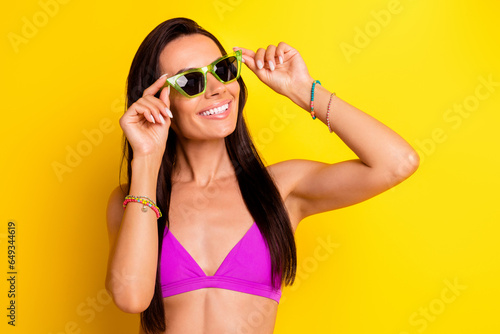 Portrait of stunning positive girl beaming smile arms touch sunglass empty space ad isolated on yellow color background