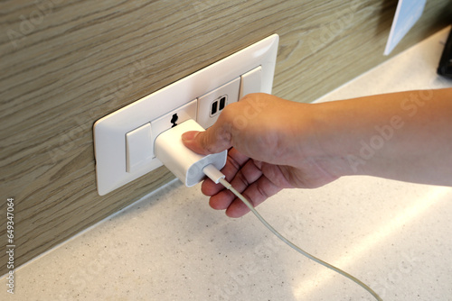 Hand insert a plug of the phone charger into socket. photo