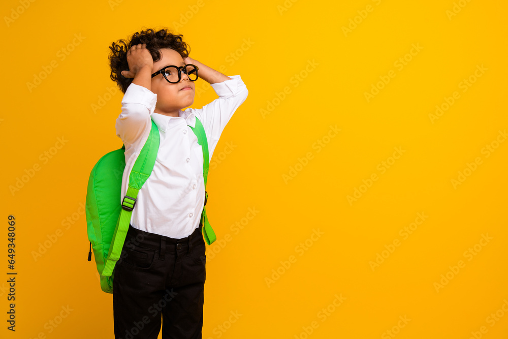 Photo of impressed schoolchild hands touch head look empty space ad carry backpack isolated on yellow color background Photo of impressed schoolchild hands touch head look empty space ad carry backpack isolated on yellow color background