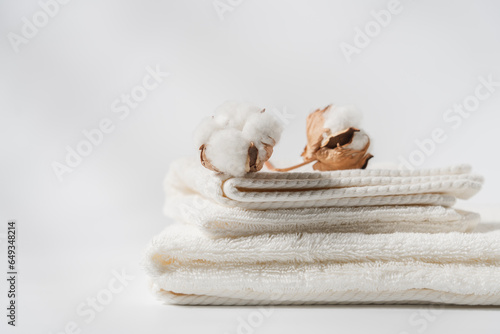 Fototapeta Naklejka Na Ścianę i Meble -  Stack of cotton towels and cotton flower buds close up view on white background with copy space