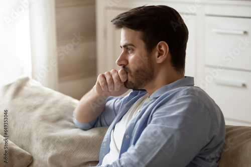 Thoughtful upset man pondering problem solving, making difficult decision close up, touching chin, sitting on couch alone, frustrated stressed guy feeling lonely, break up with girlfriend