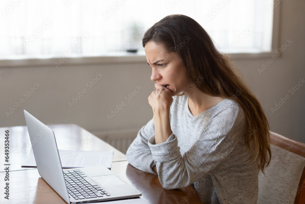 Nervous unhappy woman looking at laptop screen, biting nails, reading bad news online, dismiss notification or unpaid debt, stressed female student or freelancer working on difficult project Nervous unhappy woman looking at laptop screen, biting nails, reading bad news online, dismiss notification or unpaid debt, stressed female student or freelancer working on difficult project