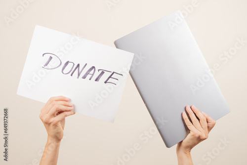 Donation technology to charity. Volunteer hands holding laptop computer and paper board with word Donate