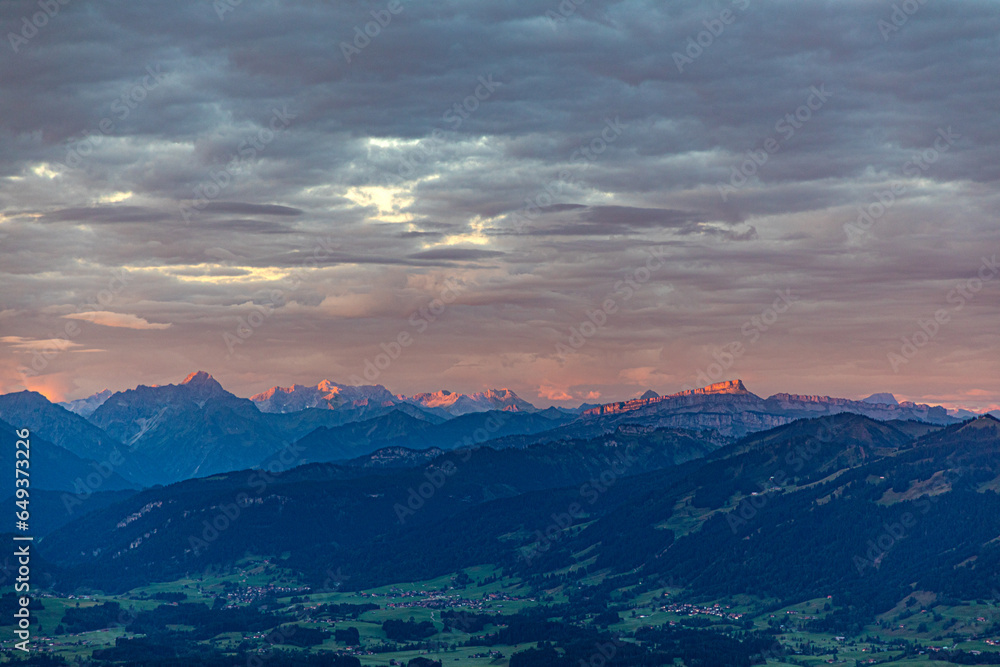 sunrise seen from mountain peak of Gruenten with village of Rettenberg and Alps panorama