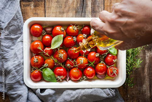 Photos tomates en una bandeja de horno siendo rociados con aceite de oliva