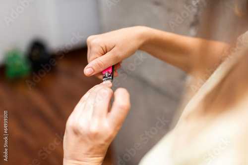 Woman's hands cutting and grooming their nails with a nail clipper. manicure at home
