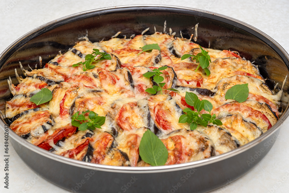 Eggplants with tomatoes baked with cheese and garlic sauce and sprinkled with basil leaves.