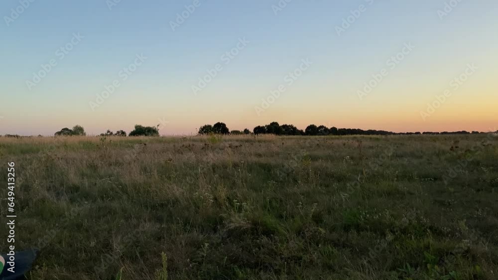The sun sinks below the horizon, casting a golden glow over the field. Woman in yoga gear sits on yoga mat, eyes closed, hands in a namaste pose. She is at peace with herself and the world around her The sun sinks below the horizon, casting a golden glow over the field. Woman in yoga gear sits on yoga mat, eyes closed, hands in a namaste pose. She is at peace with herself and the world around her