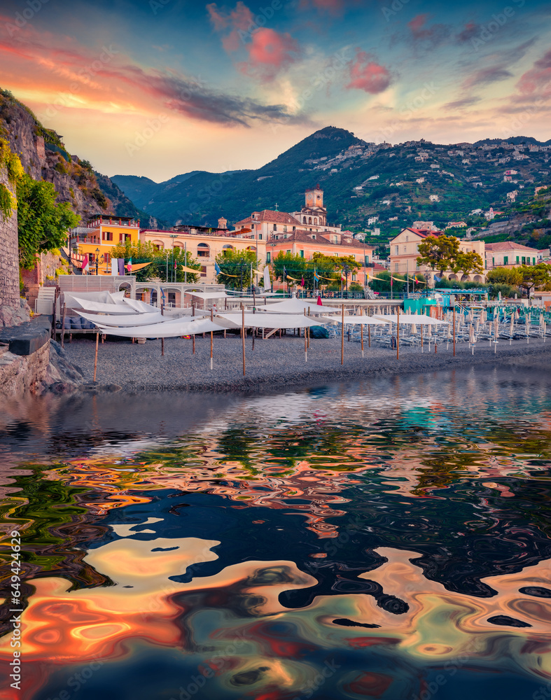 Minori public beach and town on the hill reflected in the calm waters Mediterranean sea. Stunning sunset in Italy, Salerno region, Europe. Vacation concept background.