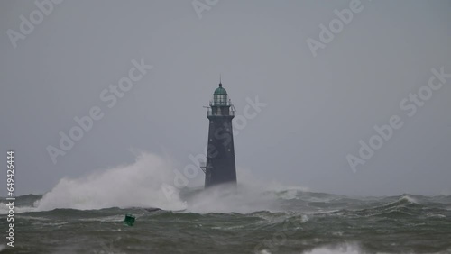 Hurricane high winds causing waves to crash against a lighthouse slow motion