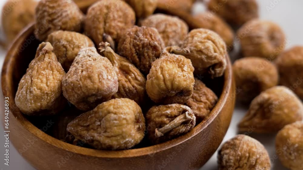 Full wooden bowl of dried figs with wrinkled peel close up. Rotation Full wooden bowl of dried figs with wrinkled peel close up. Rotation