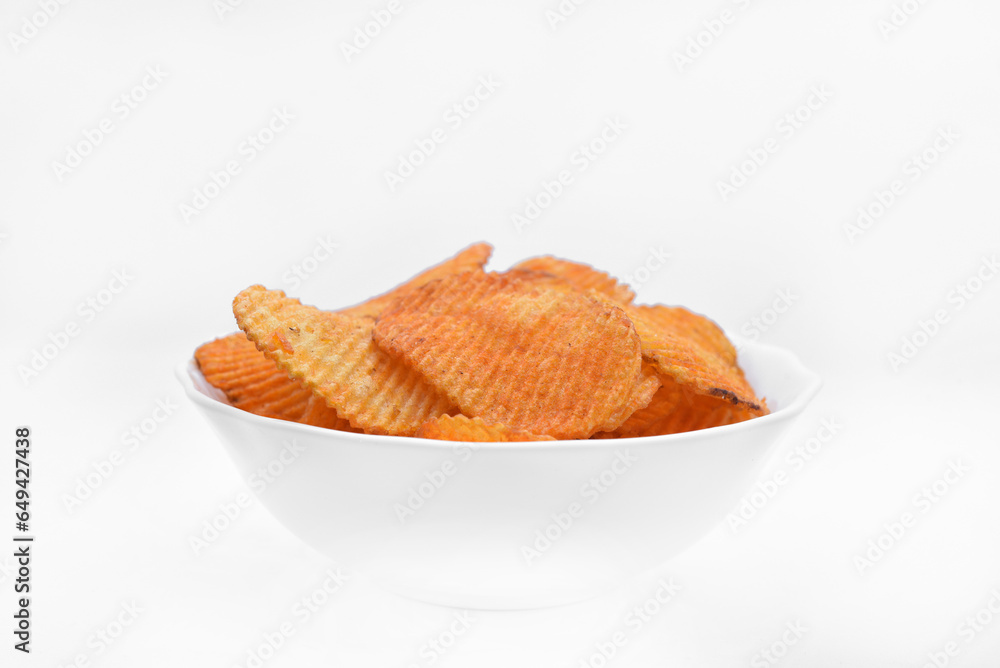 Red pieces of fried potatoes in a plate. Peppery chips on a white background. Red pieces of fried potatoes in a plate. Peppery chips on a white background.