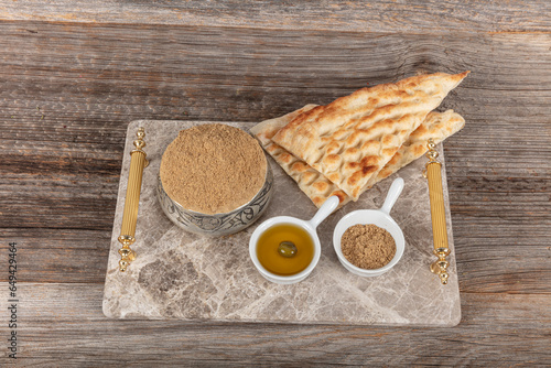 Za'atar is a culinary herb or family of herbs. It is also the name of a spice mixture typically used as a condiment, which contains the herb along with toasted sesame seeds, dried sumac, and often sal photo