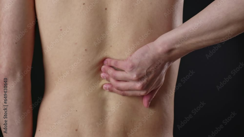 Faceless man touches, rubs his ribs near spine with hand. Relieve back pain with self-massage. Prevention and treatment of muscle spasms, scoliosis, neuralgia, injuries, spinal osteochondrosis Faceless man touches, rubs his ribs near spine with hand. Relieve back pain with self-massage. Prevention and treatment of muscle spasms, scoliosis, neuralgia, injuries, spinal osteochondrosis